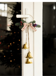 Close-up of Christmas door hanging bells with greenery and Merry Christmas ribbon decoration