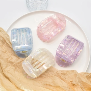 Close-up of four colorful acetic acid hair claws in shell texture on a white ceramic plate