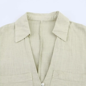 Close-up of V-neckline and button detail on light green linen texture shirt dress