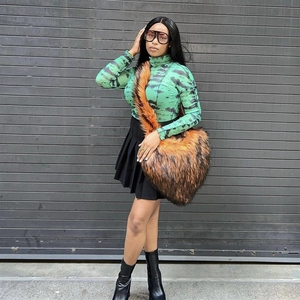 Close-up of a large brown faux fur heart-shaped crossbody bag worn with tie-dye top