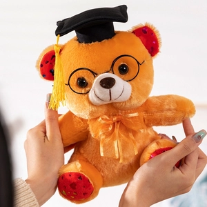 Close-up of a plush graduation bear with a black cap, glasses, and heart-sequin ears