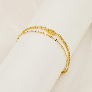 Détail du bracelet double chaîne dorée avec pendentif main de fatma sur support blanc