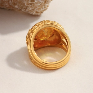 Detail of 18K gold plated ring with large yellow zircon and vintage engraved band texture
