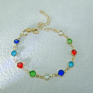 Detail of gold chain bracelet featuring vibrant multi-colored round gemstones and lobster clasp