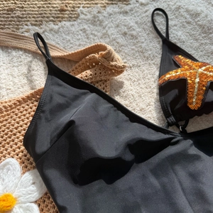 Detail of sequined orange starfish ornament on black one-piece swimsuit fabric