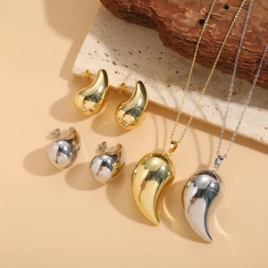 Polished gold and silver teardrop pendant necklace and earrings jewelry set on stone
