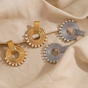 Macro detail of gold and silver textured hoop earrings with white pearls on silk background