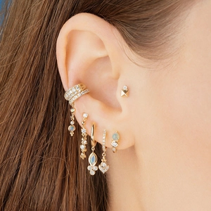Elegant gold geometric earrings with sparkling zircon stones worn by a model in close-up