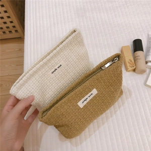 Detail of waffle weave texture cosmetic pouch with simple wish label and top zipper