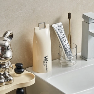 Cream portable travel toothbrush holder and rinse cup on a minimalist stone counter