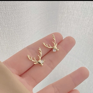 Detailed close-up of gold reindeer stud earrings featuring a sparkling crystal stone