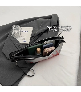 Detail showing the spacious interior of a splatter art crossbody bag with daily essentials