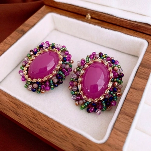 Macro detail of vintage floral earrings with purple oval crystals and colorful bead trim