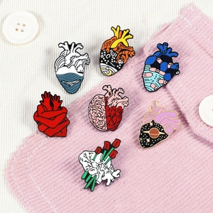 Creative anatomical heart and brain enamel pins set on a pink corduroy jacket