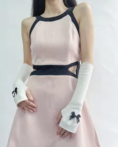 Detail of white knit arm sleeves with black ribbon bows and pearl charms on pink dress