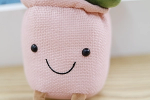 Close-up of pink plush tulip plant toy with cute black embroidered smiley face detail