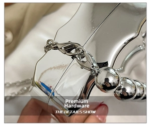 Detail of silver shell leaf evening bag with metallic chain and sphere bead hardware