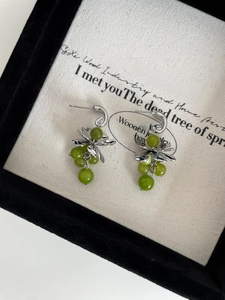 Detailed macro view of silver-tone flower stud earrings with green grape-like crystal beads