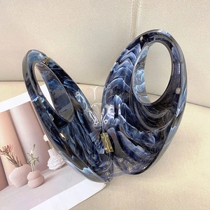 Detail of blue marble acrylic handbag with wavy texture and gold metal hinges