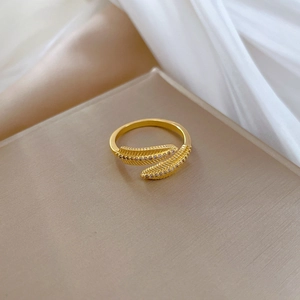 Detailed view of a gold feather ring with micro-pave crystals on a silk background