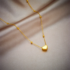 Collier élégant avec pendentif cœur doré et perles sur fond en soie champagne