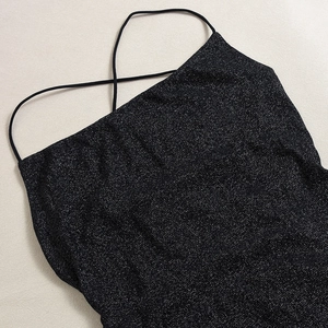Close-up of black sequin fabric texture with crossover thin straps for party dress