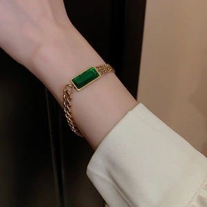 Gros plan détaillé d'un bracelet gourmette doré avec une pierre précieuse émeraude