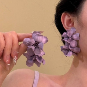 Detailed view of layered dark purple fabric flower earrings with realistic stamen details