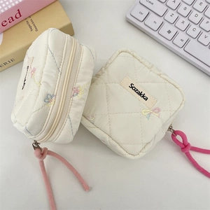 Close-up of quilted sanitary storage bags with butterfly embroidery and colorful zip pulls