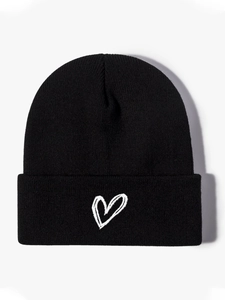 Close-up of black knitted beanie featuring delicate texture and white heart embroidery