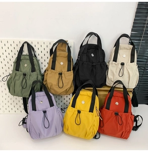 Multiple colors of lightweight nylon backpacks displayed on a white pegboard background