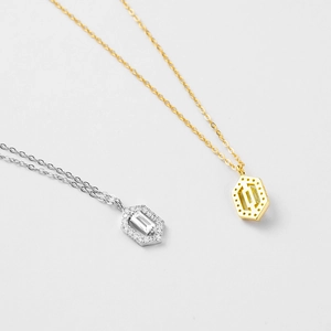 Detail of silver and gold hexagonal pendant necklaces with sparkling central crystals