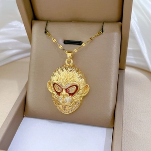 Macro detail of gold plated monkey pendant with white crystals on a jewelry box