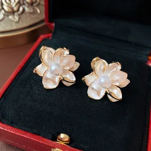 Elegant floral pearl stud earrings with gold edges on a vintage red velvet jewelry box