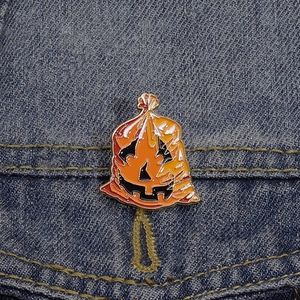 Spilla smaltata di Halloween con zucca arancione su tessuto di jeans blu denim