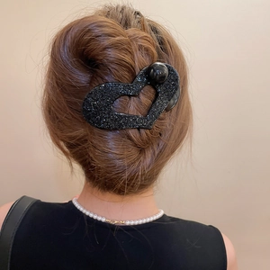 Detail of a black heart acrylic hair claw clip with shimmering glitter and oversized pearl
