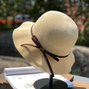 Close-up of woven straw sun hat featuring a classic brown ribbon bow detail