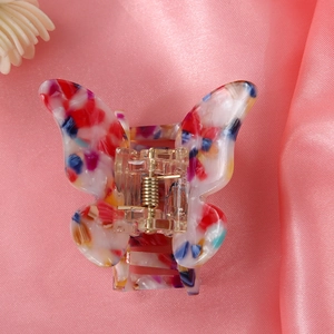 Macro shot of butterfly hair clip featuring colorful acetate patterns on pink silk