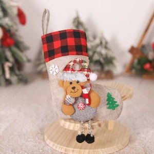 Detail of Christmas stocking featuring plush bear, red plaid cuff, and burlap texture