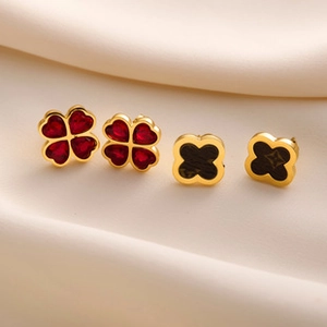 Macro detail of four-leaf clover stud earrings with red inlay and monogram pattern