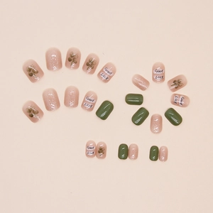 Detail of short square press-on nails with green clover design and glitter pink finish