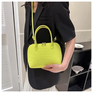 Close-up of lime green shell bag featuring crocodile embossed texture and gold zippers