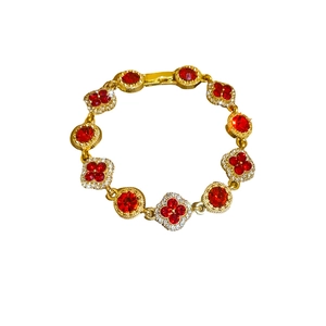 Vintage gold clover bracelet featuring red gemstone and pave diamond inlays on white background