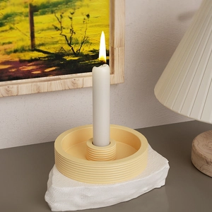 Porte-bougie jaune minimaliste avec bougie blanche sur un socle en pierre brute
