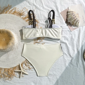 Flat lay of cream two-piece bikini featuring scallop trim and gold bead accents on straps