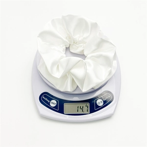 Detail shot of a cream satin scrunchie weighing 14.7g on a digital scale for accuracy