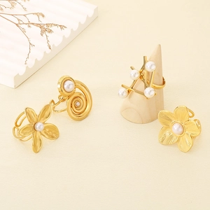Detailansicht von vier goldenen Edelstahlringen mit Perlenakzenten und Blumendesigns