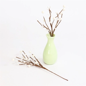 Close-up of artificial white berry branches in a ceramic vase for festive home decoration