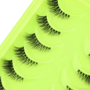 Close-up of natural black half-eyelashes with clear bands on a vibrant green tray