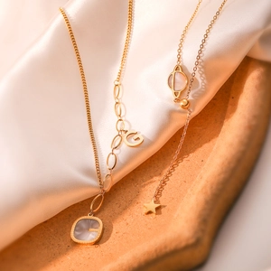 Gold plated layered necklaces with shell star moon pendants on silk background